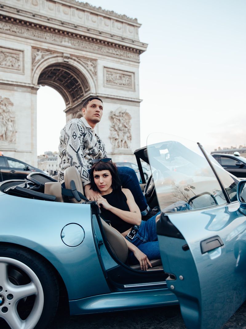 Couple in a vintage convertible before the Arc de Triomphe, Paris
